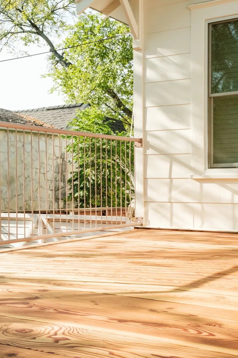 Timber boards running along a white house with a metal railing at the open edge
