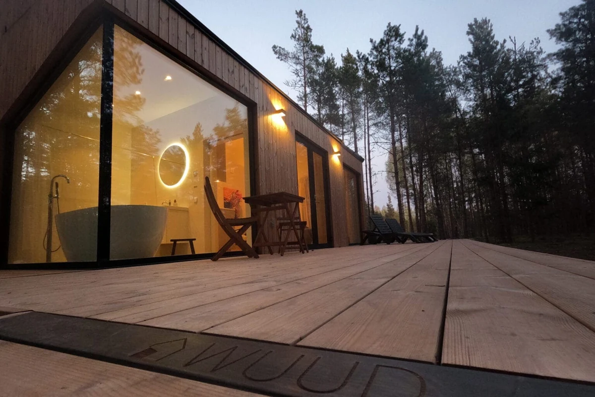 Broad Thermory spruce decking beside a warmly lit cabin in a forest